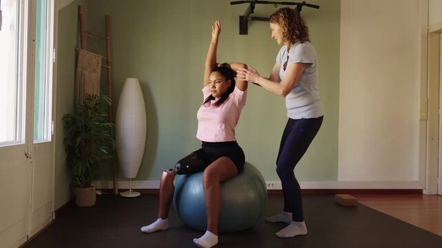 Amputee woman stretching arm with physical therapist assistance