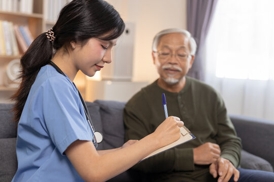 Nurse providing home healthcare consultation to senior man, taking notes during visit, representing elderly care, medical support, patient monitoring, home service.