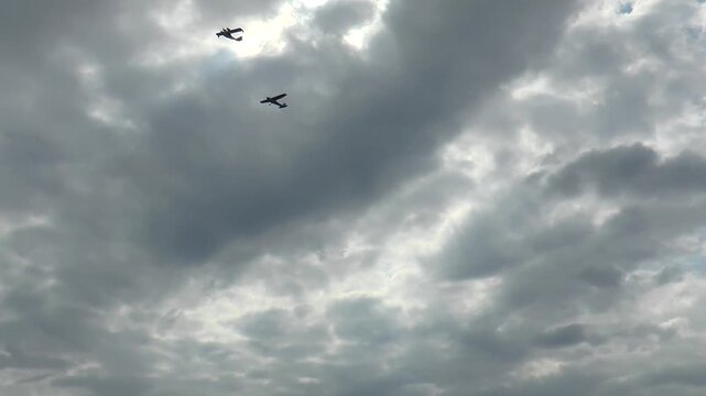  Two small sports plane flying against the backdrop of a cloudy sky.