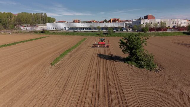 Agricultural Harmony: A tractor cultivates a vast field under a clear, blue sky, symbolizing the symbiotic relationship between agriculture, nature, and industry.
