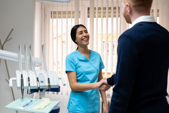 Smiling dental professional shaking hands with a patient in a modern clinic