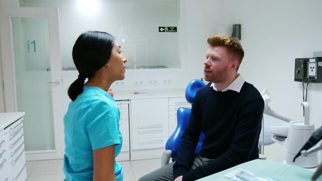 Young man explaining his tooth problem to a female dentist during a consultation in a dental clinic