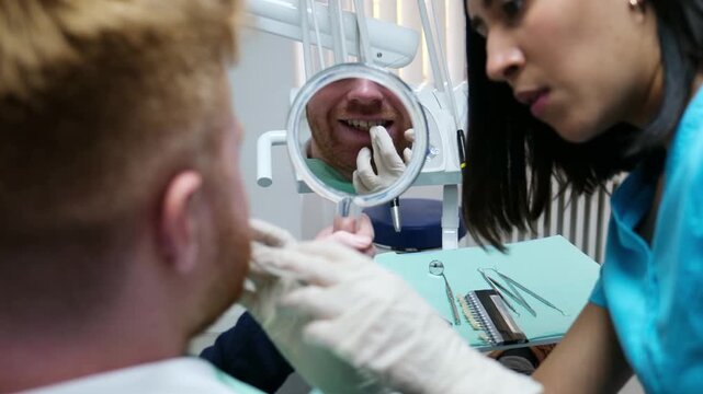 Young man examining his smile in a mirror during a dental consultation with his dentist