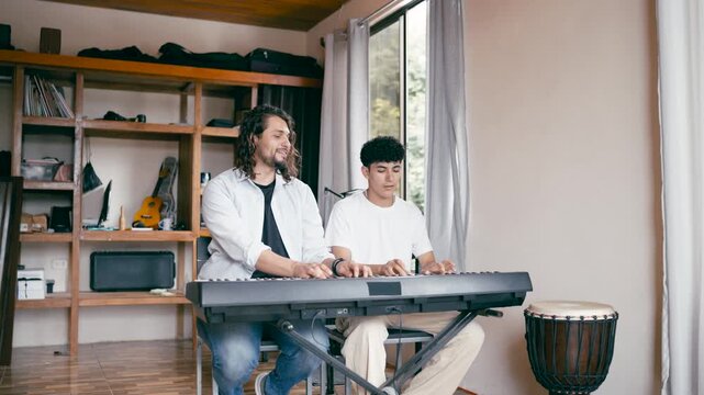 Young man learning to play the piano with his private teacher. Enthusiastic tutor and student practicing together on an electronic keyboard