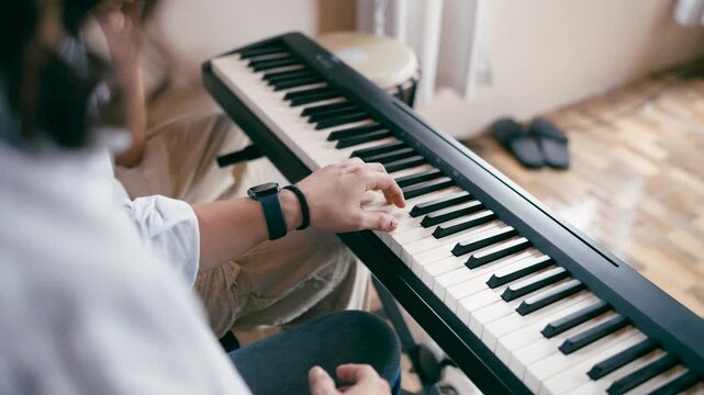 Male music teacher demonstrating a melody on a digital piano. A dedicated instructor guiding a student during a private educational session