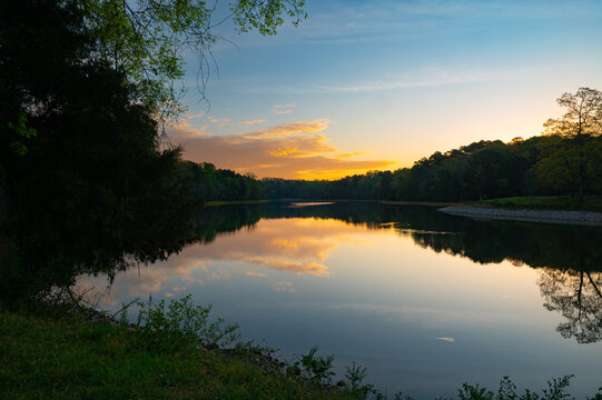 A gentle and quiet sunrise reflected in the mirrored water of Chickamauga Lake in Booker T. Washington in Tennessee
