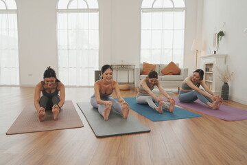 Obraz premium A group of four beautiful Asian women in sports bras meet and greet each other before starting their yoga session at the studio. The concept of exercising for health is reflected in their work.