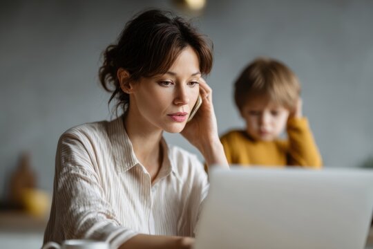 working mother using laptop while child distracts her remote work family balance concept