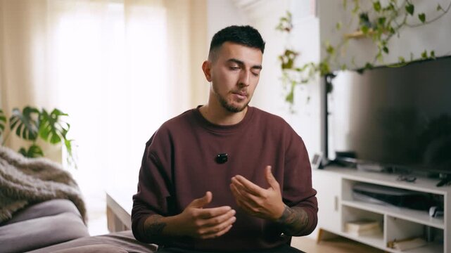 Confident young man with tattoos talking and gesturing while recording a video blog. Vlogger creating content for his social media channel