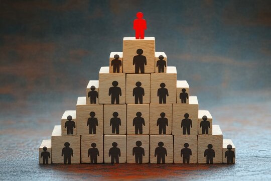 red figure standing atop pyramid of wooden blocks with black person icons, symbolizing leadership, hierarchy, authority and isolation