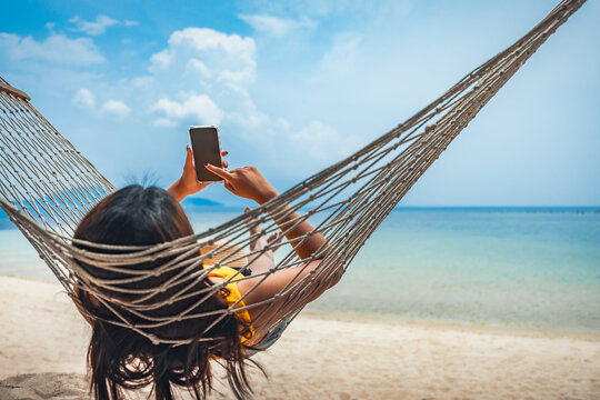 Traveler asian woman relax and use mobile phone and travel in hammock on summer beach at Koh Rap Samui in Surat Thani Thailand