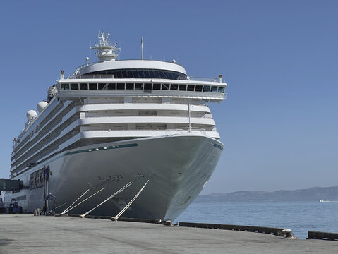 Modern cruiseship or cruise ship liner Serenity docked at terminal pier Piraeus Athens, Greece with harbor infrastructure and marine traffic panoramic city skyline view Mediterranean summer cruising