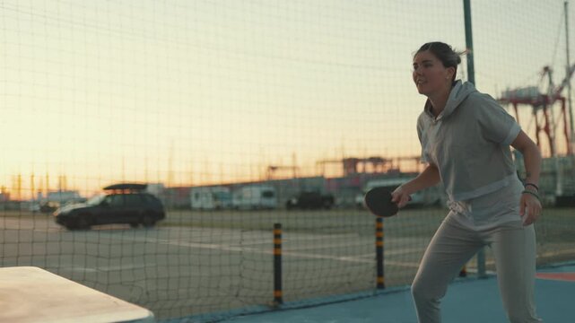 Frustrated woman losing a table tennis game at sunset