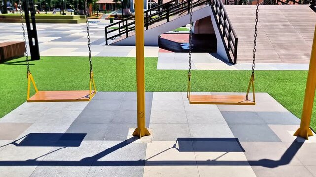 Sidoarjo, Indonesia 5 April 2026: Empty Playground Swings in Modern City Park Under Bright Blue Sky