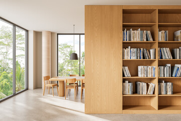 Bright minimal interior with wooden dining table, chairs, and large bookshelf beside expansive...