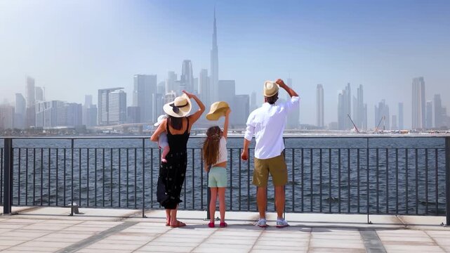 A happy tourist family of four looks at the urban skyline of Dubai, UAE, during their city vacations