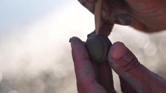 Pottery sculpting hands, close-up on a person's hands crafting a small clay object with a tool