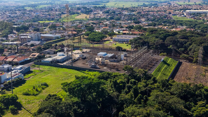 Fototapeta premium An aerial view of a small town surrounded by lush green forests and fields on a sunny day