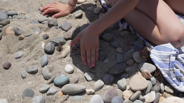 Child beach stones creating a heart shape with small pebbles on a sunny day
