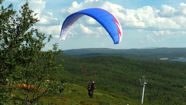 Paraglider caught the wind on the mountainside summer day. 
