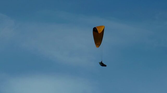 Paraglider soars over the forest on the backdrop of the picturesque cloudy sky on a summer day.