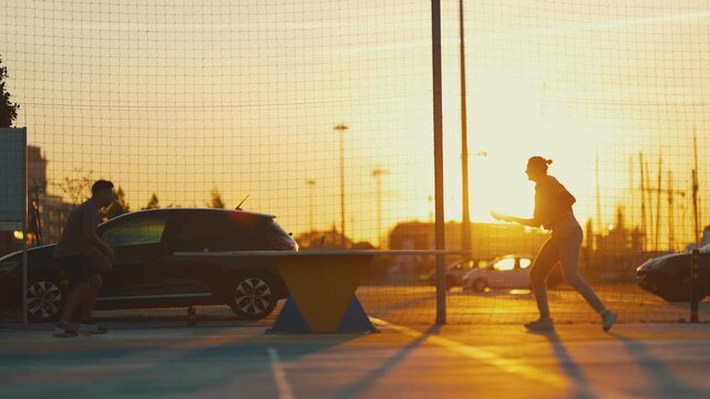 Silhouette of people playing table tennis at sunset