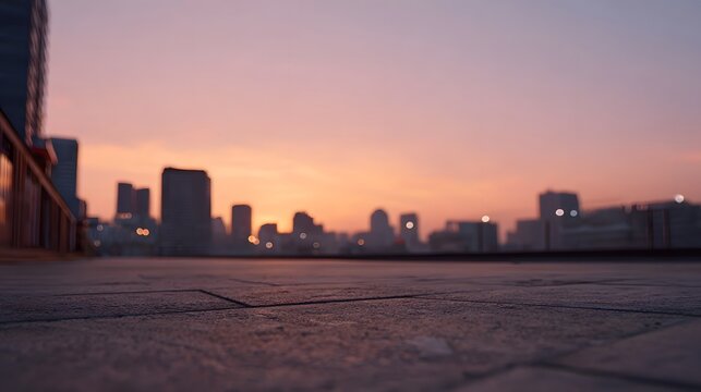 A low angle view of urban pavement leading toward a colorful sunrise city skyline