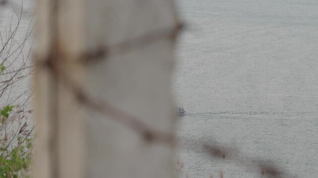 Coastal border surveillance of a fishing boat on the ocean through a wire fence
