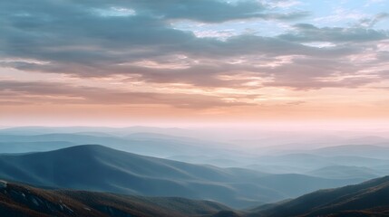 Fototapeta premium A sweeping panoramic view of receding mountain ranges under a pastel hued sunrise sky