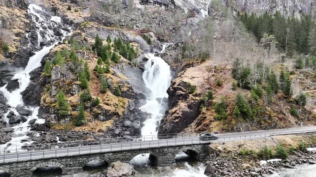 L&aring;tefossen is a famous twin waterfall located in Odda, Vestland, Norway. The powerful waterfall flows down between steep mountains and crosses under a historic stone bridge. Scenic landscape and popul