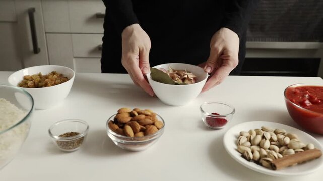close-up of hands holding a bowl filled with garlic cloves and bay leaves, emphasizing the aromatic flavor base used to cook a fragrant rice and chicken dinner