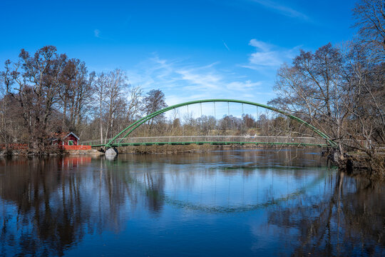The New Five-Penny bridge and the old bridgekeepers cottage at waterfront park &Aring;backarna across Motala Stream during early spring 2026 in Norrk&ouml;ping, sweden. The bridge opened March 7, 2025.