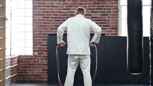 Martial arts tying kimono Gi jiujitsu karate brown belt, traditional, belt, blurred out background video, selective focus cinematic, gym setting