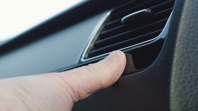 Person adjusting car air vent flow direction