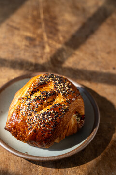 Smoked salmon everything croissant on a wood surface and window shadow  