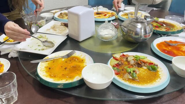 Hands collecting leftovers from a restaurant table into containers