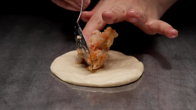 Closeup sequence of raw dough on dark surface gradually filled with seasoned minced meat, illustrating the initial preparation stage of homemade stuffed pastry