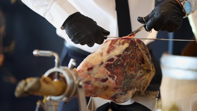 A man cuts dry-cured prosciutto crudo (uncooked, unsmoked ham).