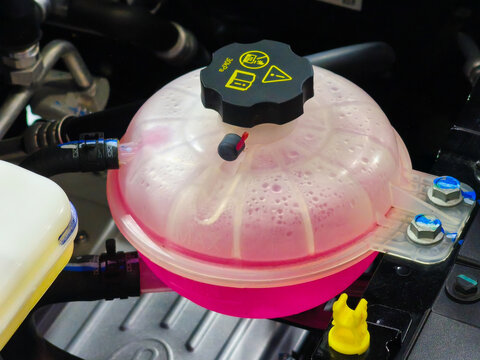 Car Coolant Expansion Reservoir Tank with Pink Antifreeze in Engine Bay