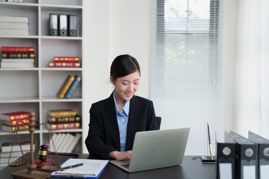 Female lawyer working on laptop at her office desk, specializing in legal service, justice, and advocacy, preparing documents for a court case and advising clients