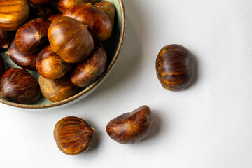 Obraz premium Chestnuts in bowl on white background with copy space
