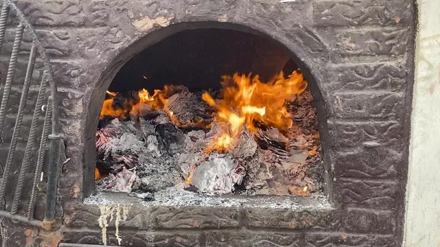 A fire burns in a fireplace. Wood and paper burning in a fireplace to keep warm.