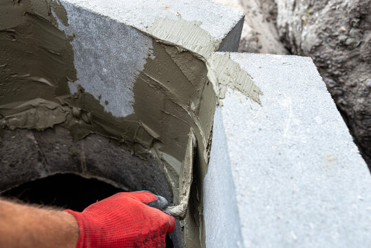 Worker applying mortar to concrete blocks for septic tank
