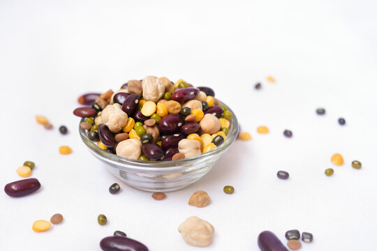 Many dried multi-colored beans closeup, an assortment of various kidney beans and peas on a white background in a glass bowl. Healthy eating, Protein intake concept.