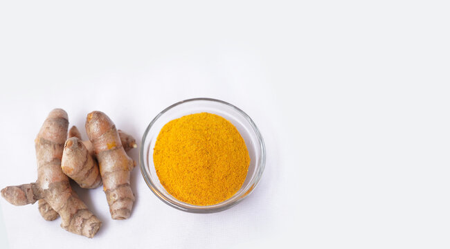 Aromatic turmeric or Haldi powder in glass bowl and fresh raw roots isolated on white background, Indian spice and Natural herb concept.