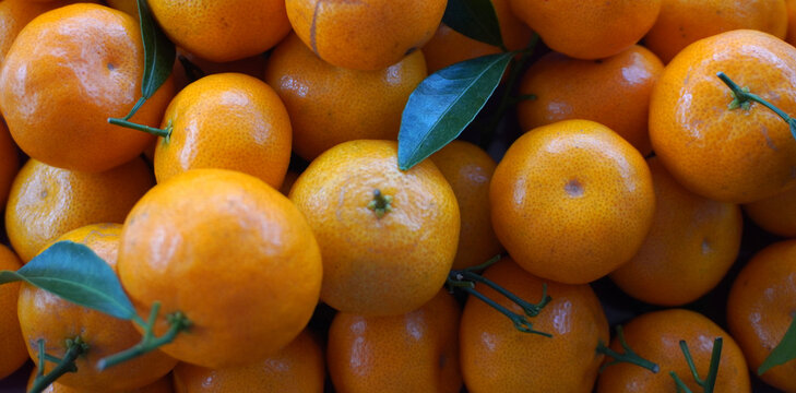 Top view of a pile of fresh orange mandarin oranges with green leaves. Full frame background of ripe sweet tangerines or clementines, ideal for healthy food and harvest concepts. jeruk santang madu