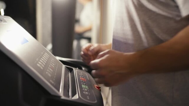 Close-up of a treadmill control panel during a home workout. Treadmill console with speed and incline buttons. A man's hand is visible near the controls. Concept of cardio training, fitness technology