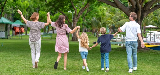 Fototapeta premium Happiness family outdoor joyful enjoying nature bonding in nature intergenerational happiness. Multigenerational family walking in park outdoor fun lifestyle relaxing smiling walking connection