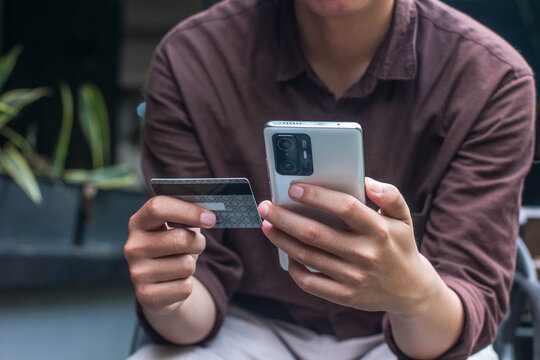 Man holding credit card and smartphone for online payment, illustrating fintech, e-commerce, and secure digital transaction in modern cashless society