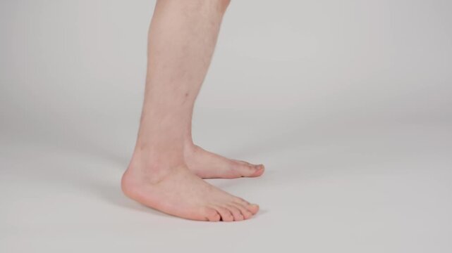 Close-up view of a person's flat feet walking in slow motion, highlighting pes planus condition, foot arch collapse, and over pronation on a white background